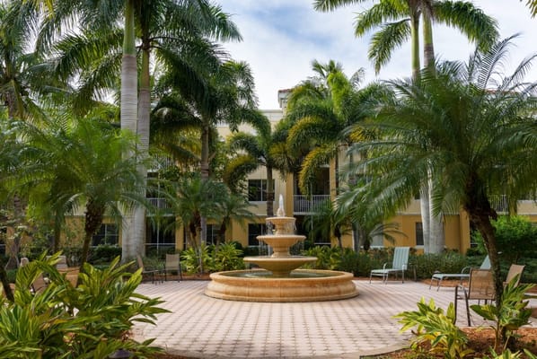 A decorative fountain surrounded by palm trees and lounge chairs