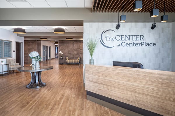Modern reception area with a wooden front desk and seating.