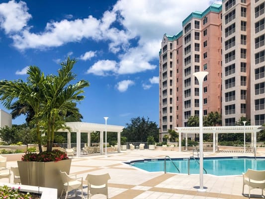 Outdoor pool surrounded by lounge chairs and gardens at The Glenview at Pelican Bay