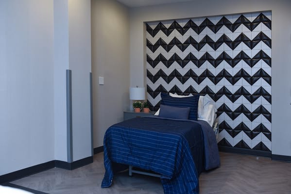 A cozy bedroom with a patterned accent wall and neatly made bed.