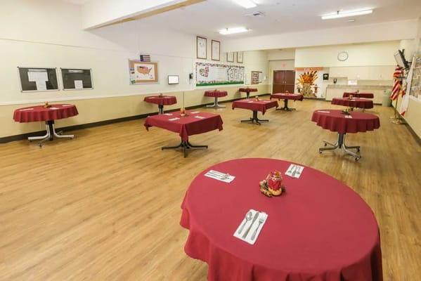 Dining area with red tablecloths and utensils set up.