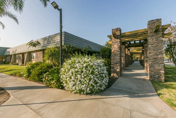 Pathway lined with flowers leading to a stone pergola at The Hills Post Acute.