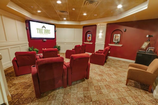 Cozy theater room with red seating and a large screen