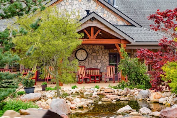 A view of the entrance with red rocking chairs and a stone wall.