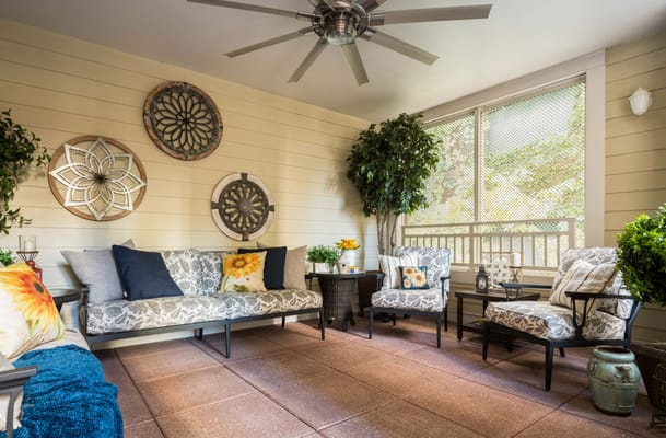 Sunroom with comfortable seating, plants, and decorative wall art.