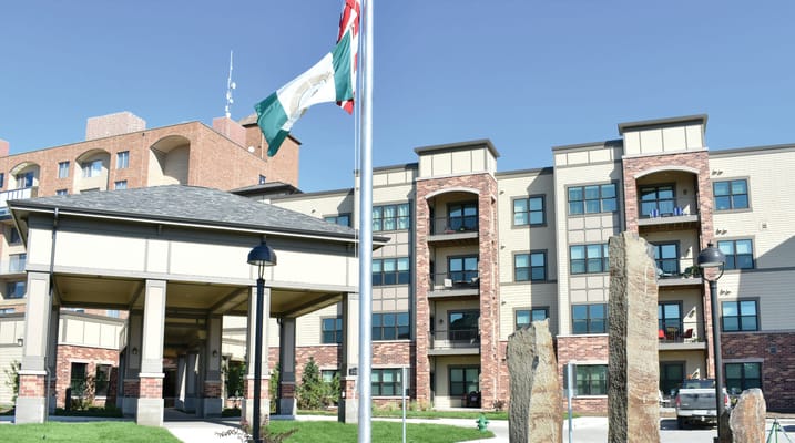 Exterior of The Lindens at Green Hills with flags and stone structures.