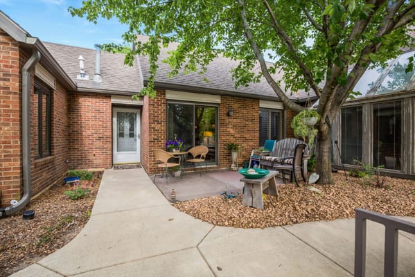 Cozy patio with seating and plants outside a resident's unit.