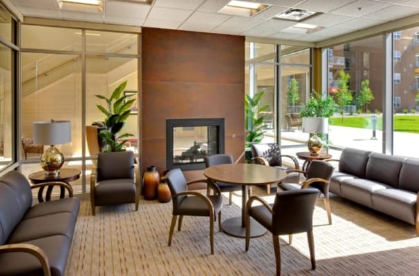 A cozy living room with seating, a fireplace, and plants.