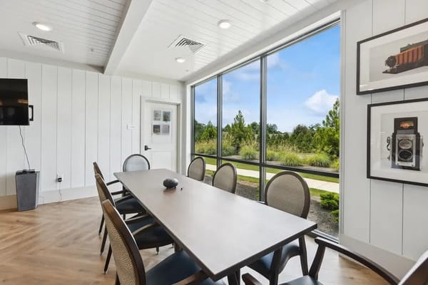 Bright conference room with a large table and windows overlooking greenery