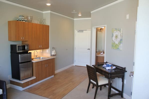 A kitchenette and living area in a senior living facility room