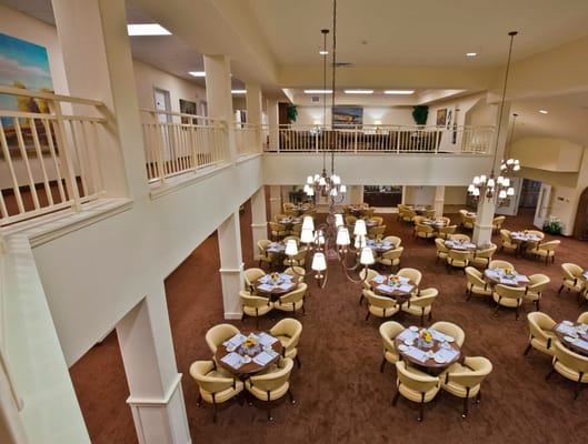 Bright dining area with round tables and yellow chairs.
