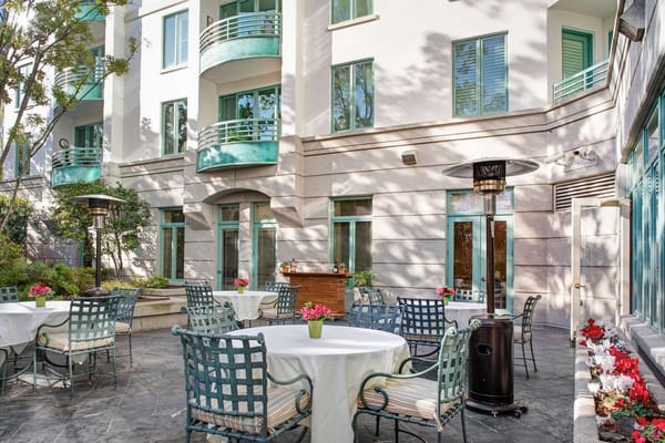 Patio seating with tables and greenery at The Stratford senior living facility