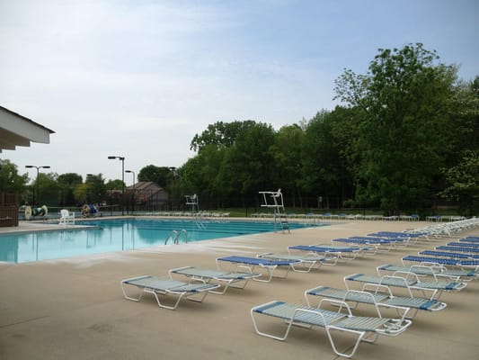 Outdoor swimming pool with empty lounge chairs and surrounding greenery
