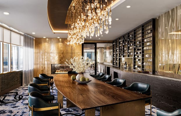 Stylish lounge with a large wooden table, plush chairs, and a decorative pendant light.