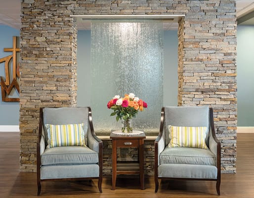 Comfortable seating area with water feature and floral arrangement