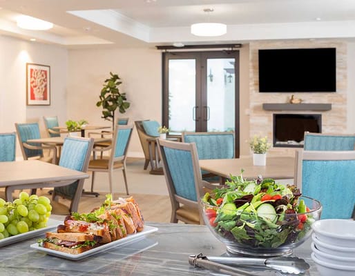 A well-decorated dining area with tables, chairs, and a salad and sandwich platter.