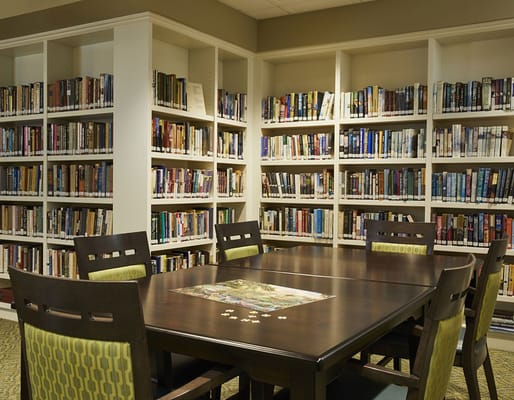 Interior of a library with bookshelves and a wooden table.