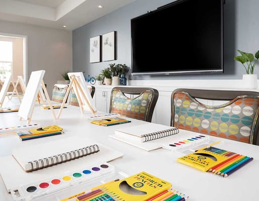Well-lit art activity room with easels and art supplies on a table.