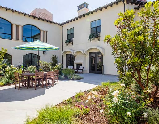 Outdoor dining area with a table and chairs under an umbrella.