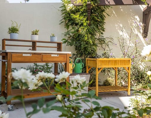 Wooden gardening tables and potted plants in a serene garden setting.