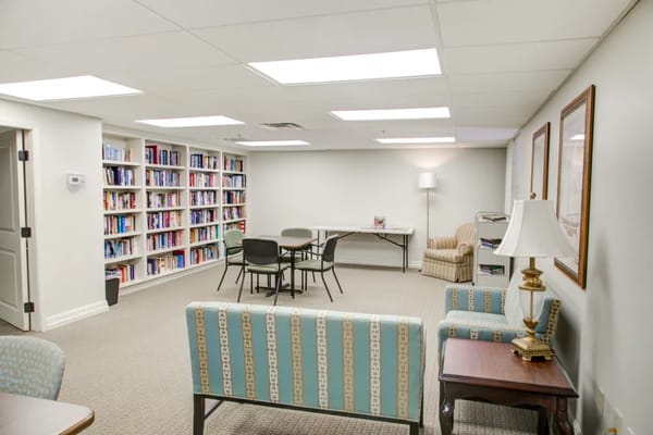 A library area with bookshelves, seating, and a table in Truewood by Merrill.