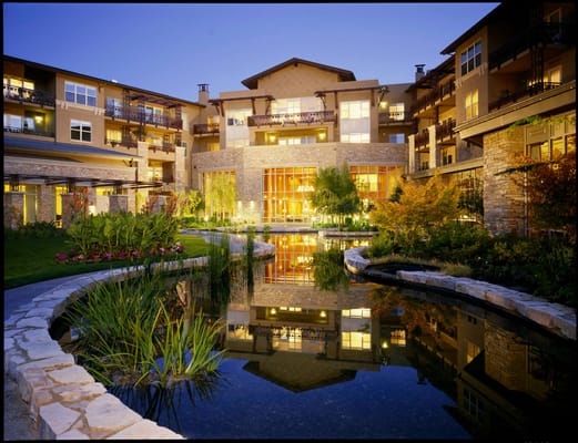 Exterior view of Vi at Silverstone illuminated at dusk, featuring a pond and landscaped gardens.