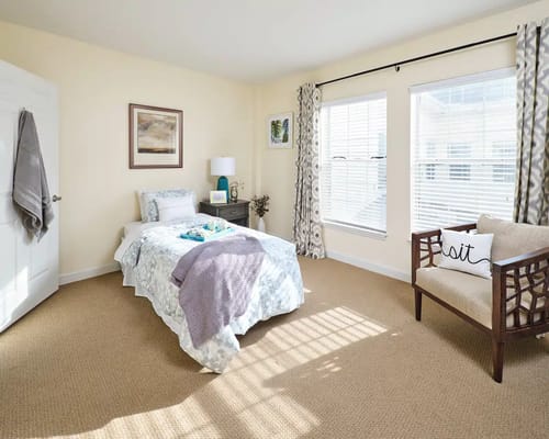 A well-decorated bedroom with a single bed, lamp, and chair.