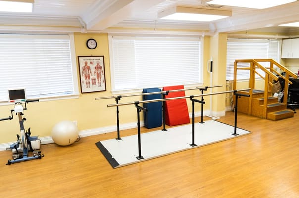 Physical therapy room with equipment and exercise bars