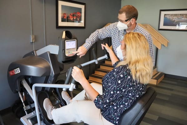 Staff assisting a resident with fitness equipment