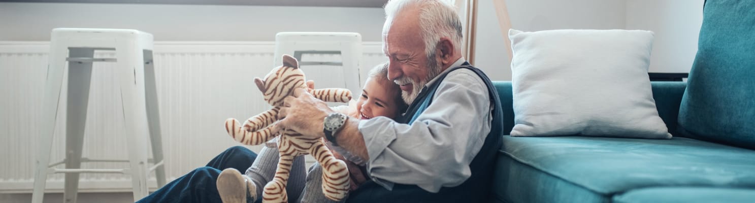 A senior man hugging a young child on a sofa