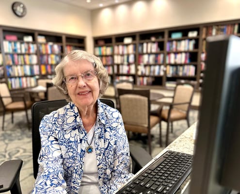 Resident engaging with a computer in a lovely library setting