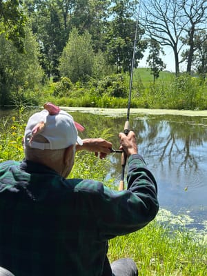 An elder fishing by a serene pond in nature