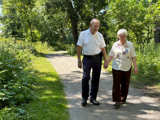 Two residents walking hand-in-hand on a garden path