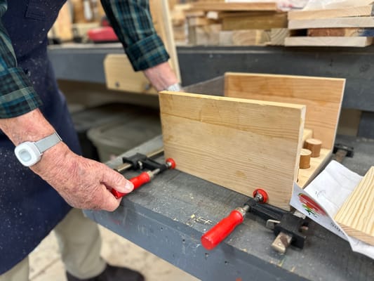 An older adult working on woodworking project in a workshop