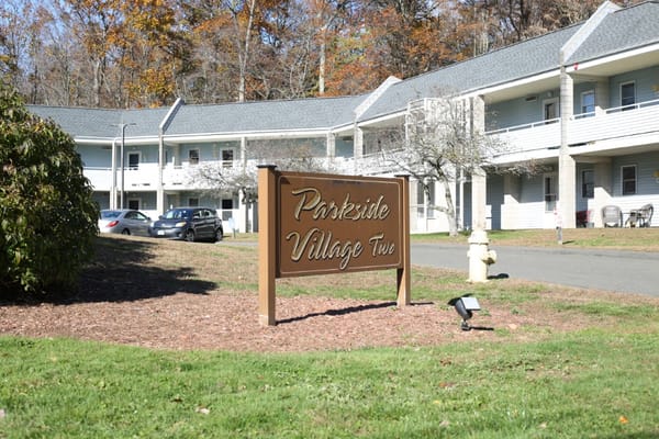 Entrance sign of Parkside Village with building in background