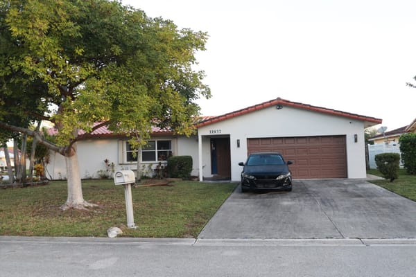 Exterior view of a home with a driveway and car