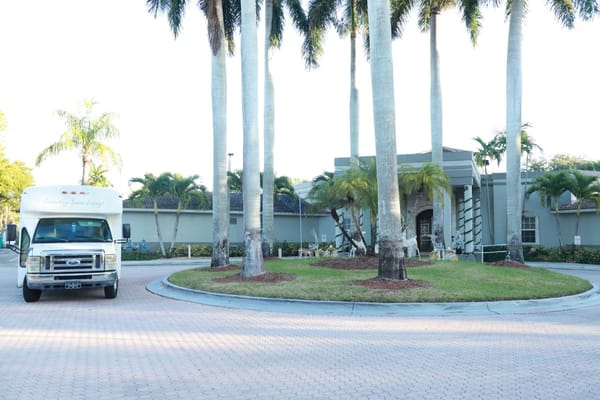 Entrance of HarborChase facility with vehicle and palm trees