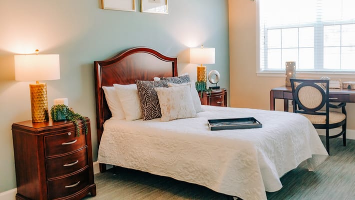 A well-decorated private resident room with a bed and desk