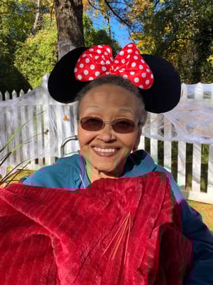 Resident wearing Mickey Mouse ears outdoors with a blanket