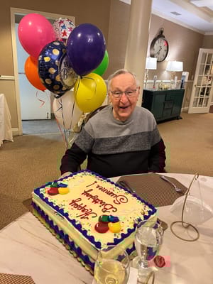 Resident celebrating birthday with cake and balloons
