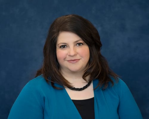 A staff member in a blue top against a blue background