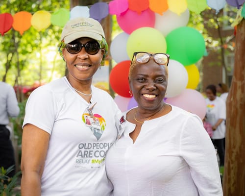 Two women smiling at a community event outdoors