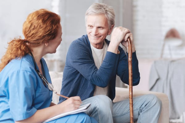 A nurse interacts with a senior man in a cozy setting