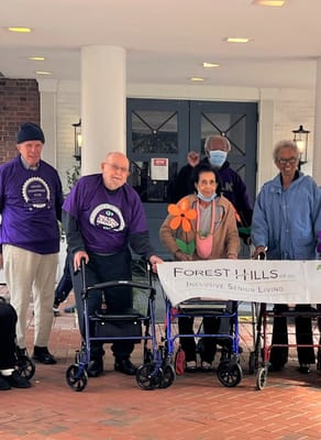 Residents and staff posing outside with a banner.