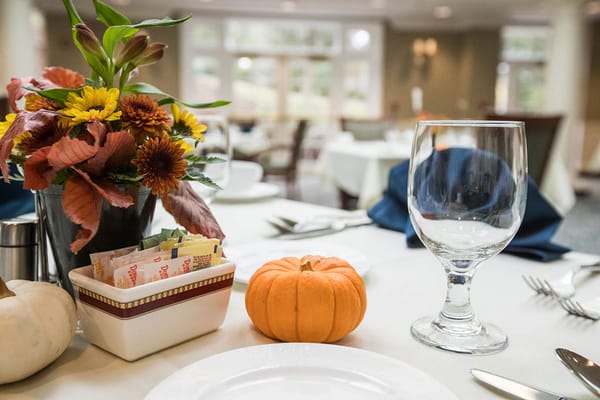 Table setting with flowers and a pumpkin in dining area
