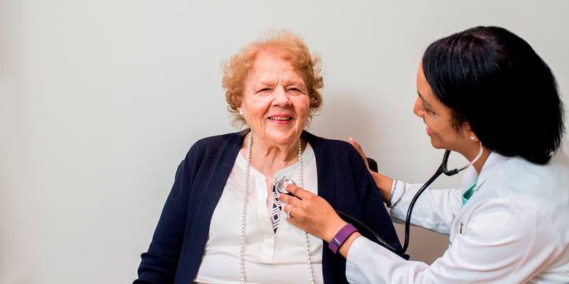 A nurse checking a patient's heartbeat in a healthcare setting.