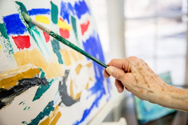 A hand painting with vibrant colors in an activity room