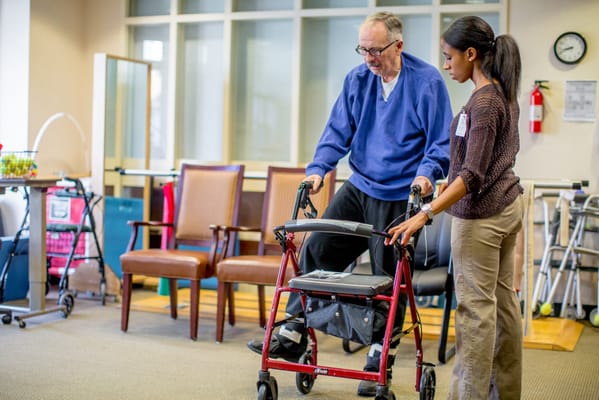 A caregiver assisting a resident with a walker in a common area