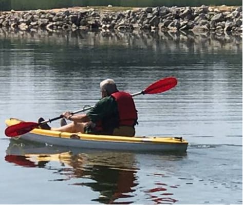 Resident kayaking on a lake with a serene backdrop