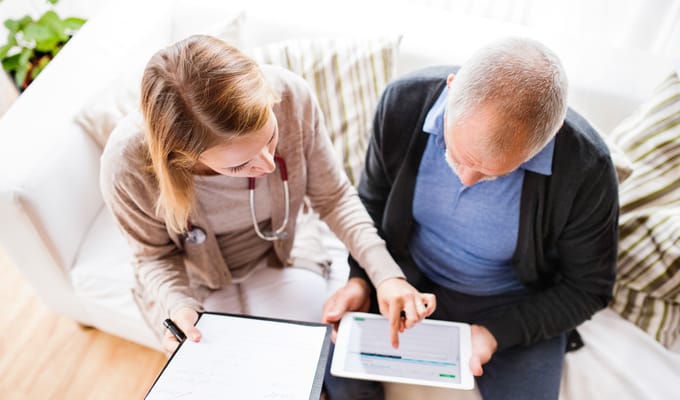 A healthcare worker and a resident discussing on a couch